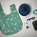 Project bag with yarn needles, scissors, stitch markers, ruler, darning needle and tin